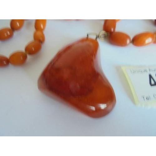 46 - An amber necklace with pendant attachment. 57.48 grams.