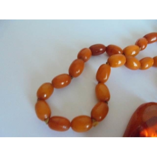 46 - An amber necklace with pendant attachment. 57.48 grams.