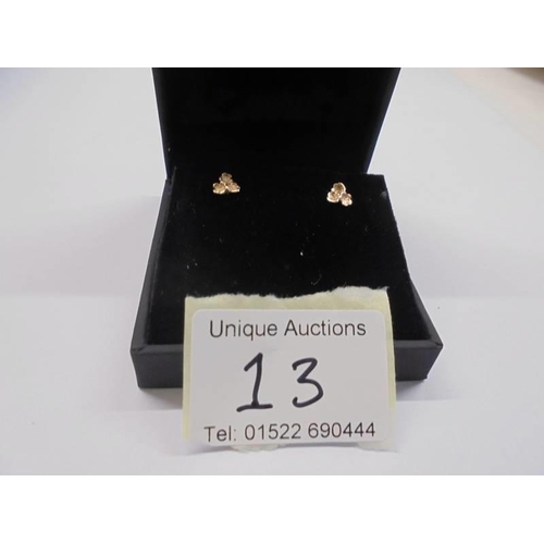 13 - A pair of 9ct gold ear studs fashioned as flower heads.