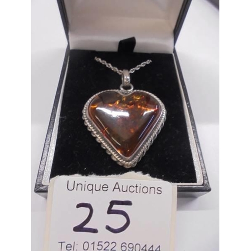 25 - An amber heart set in a silver mount with attached silver chain.