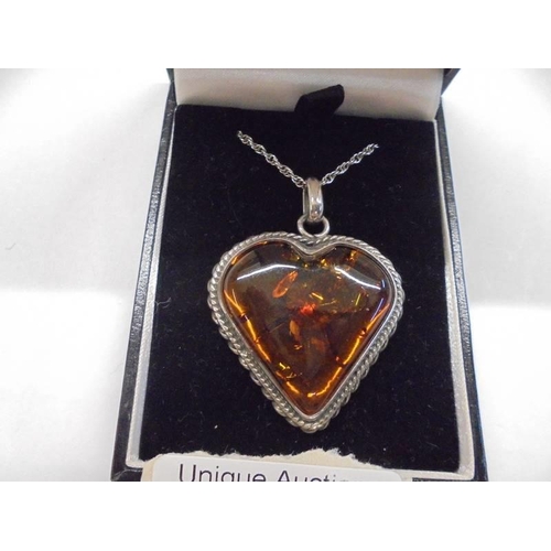 25 - An amber heart set in a silver mount with attached silver chain.