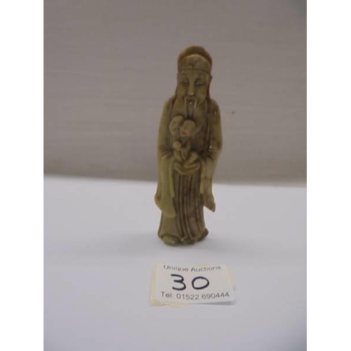 30 - A sandstone oriental figure holding a child, 11 cm.