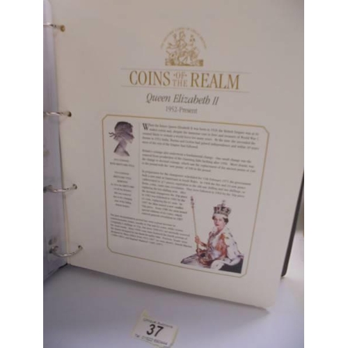 37 - A coins of the realm folder with a Queen Elizabeth II cover, a D Day cover and a replica newspaper.