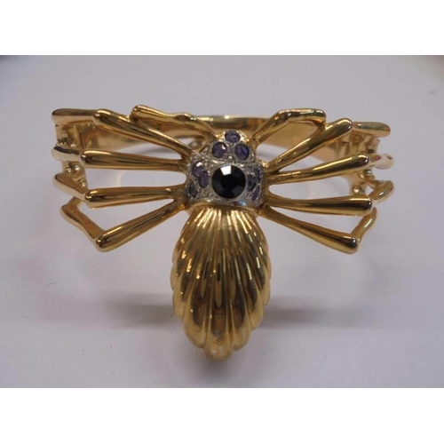 51 - A yellow metal bangle fashioned as a spider,.