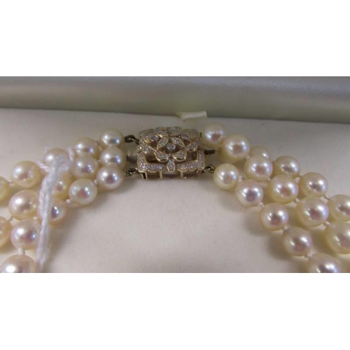 56 - A triple strand pearl necklace with 18ct and diamond clasp with original receipt.