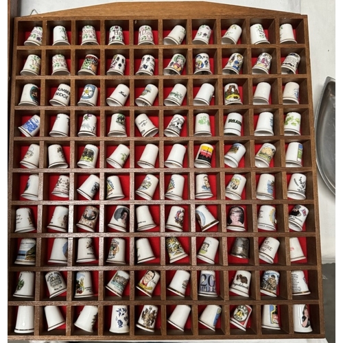 1910R - A large collection of ceramic thimbles & tourist spoons on display racks