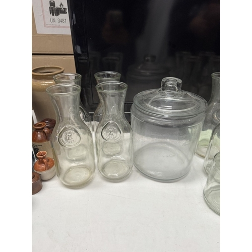 1910Y - A quantity of glass storage jars & carafes