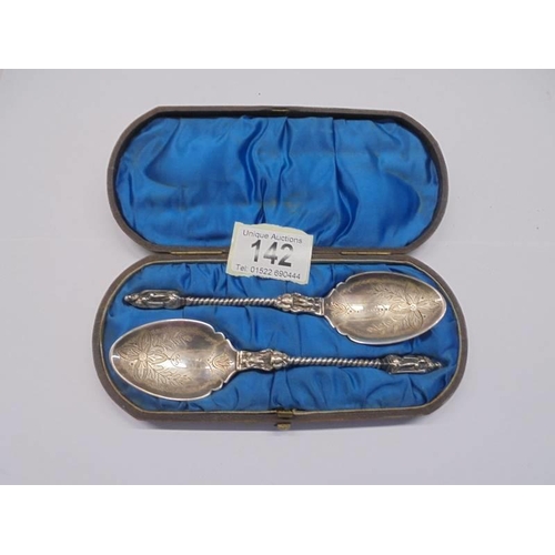 142 - A cased pair of white metal apostle spoons (test as silver).