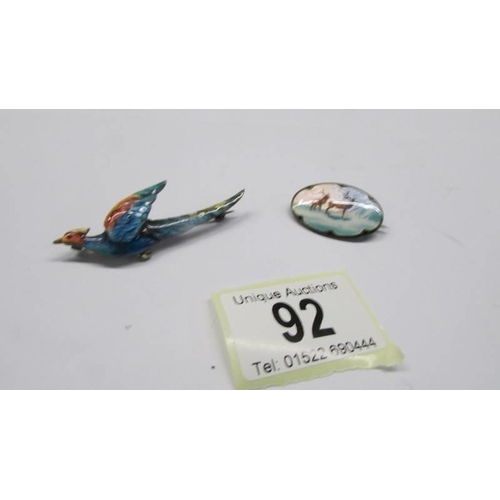 92 - A silver and enamel bird brooch and another featuring deer.