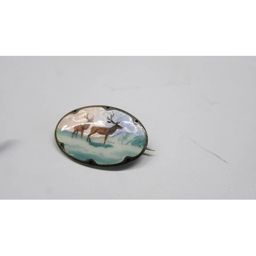 92 - A silver and enamel bird brooch and another featuring deer.