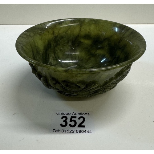 352 - A small antique spinach jade bowl carved around the exterior with archaistic dragons. 13cm diameter