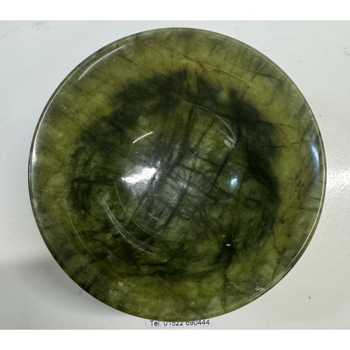 352 - A small antique spinach jade bowl carved around the exterior with archaistic dragons. 13cm diameter