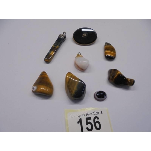 156 - Three polished stone pendants, a brooch and four other polished stones.