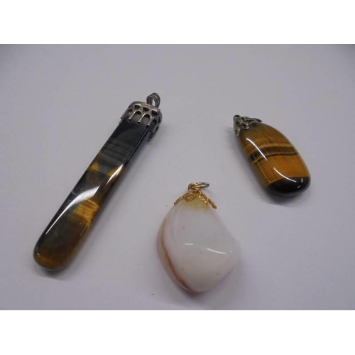 156 - Three polished stone pendants, a brooch and four other polished stones.