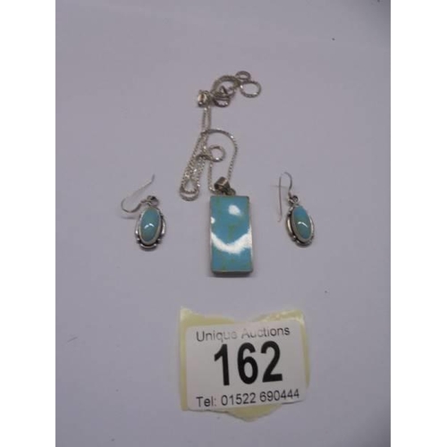 162 - A silver pendant with matching earrings set with turquoise coloured stones.