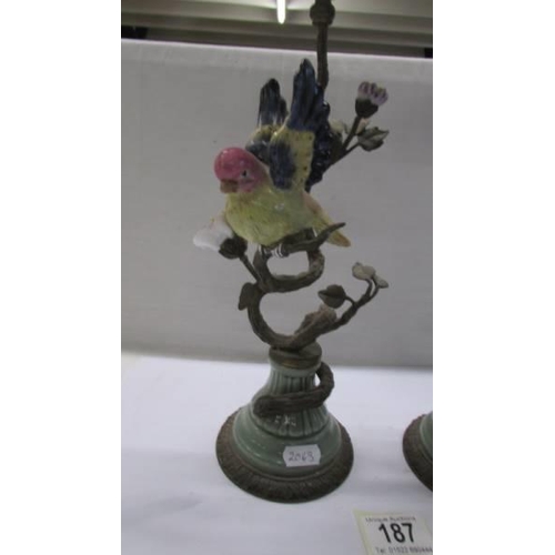 187 - A pair of 19th century metal and ceramic candlesticks surmounted birds.