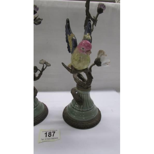 187 - A pair of 19th century metal and ceramic candlesticks surmounted birds.