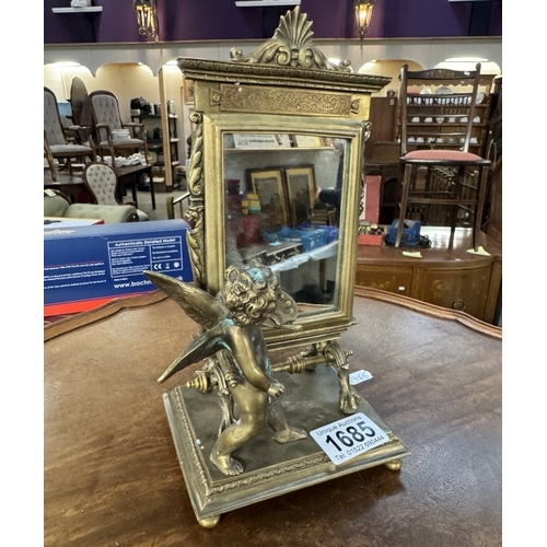 1685 - An ornate brass mirror of a cherub in front of an artists easel, base 12cm x 10cm, height 23cm