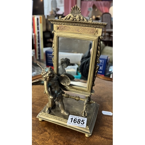 1685 - An ornate brass mirror of a cherub in front of an artists easel, base 12cm x 10cm, height 23cm