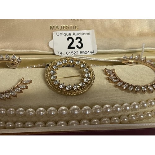 23 - A two strand pearl necklace together with a sparkly brooch and earrings.