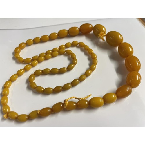 25 - A long graduated amber necklace.  51 grams in weight.