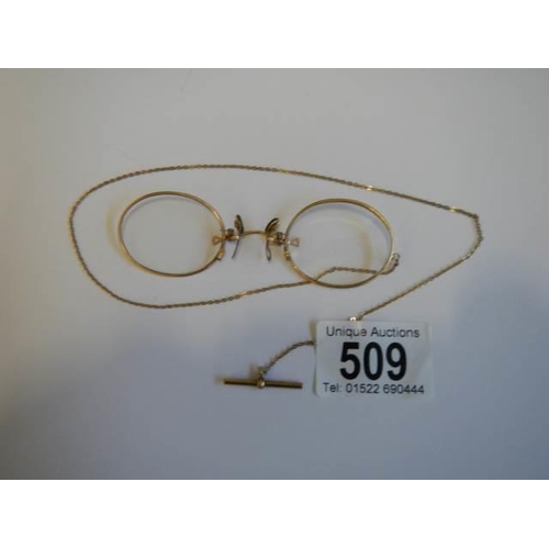 509 - A pair of Pince Nez marked V10-12k with attached chain, in good condition.