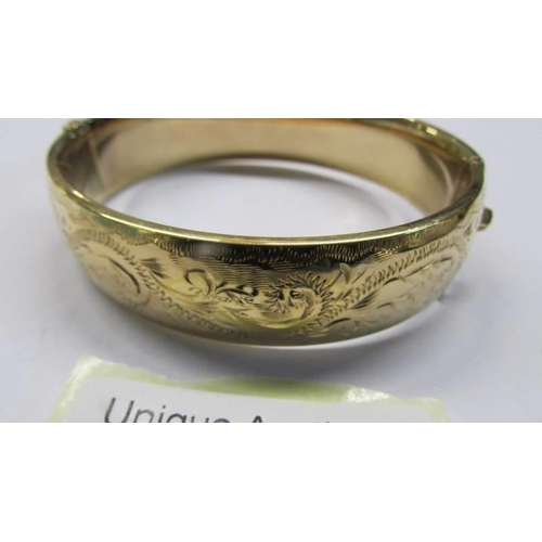 1018 - An engraved bangle marked 1/5 9ct M/C S & K.