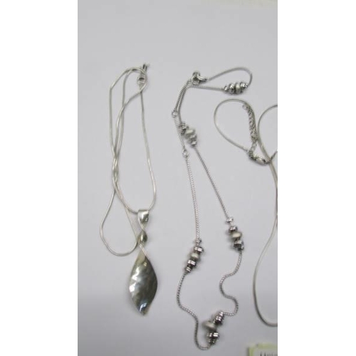 1044 - Three silver chains, a silver necklace and a silver leaf pendant.