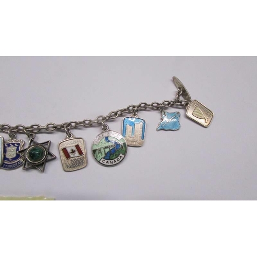 1046 - Twelve silver souvenir charms on a bracelet.