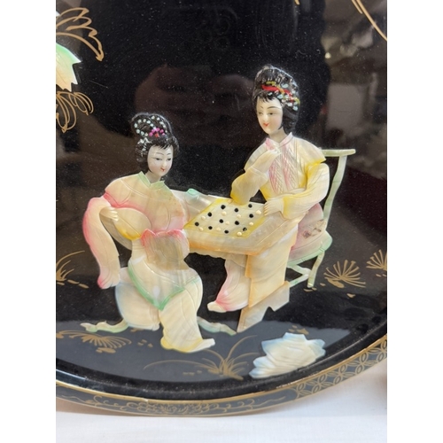 1328 - A circular oriental plaque featuring Chinese ladies in mother of pearl.