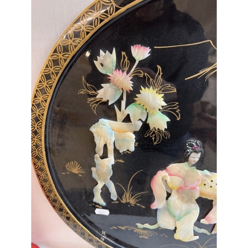 1328 - A circular oriental plaque featuring Chinese ladies in mother of pearl.