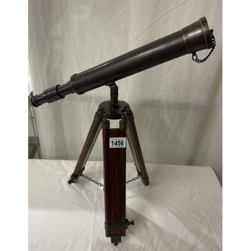 1456 - A patinated brass telescope on tripod base. Length 43cm