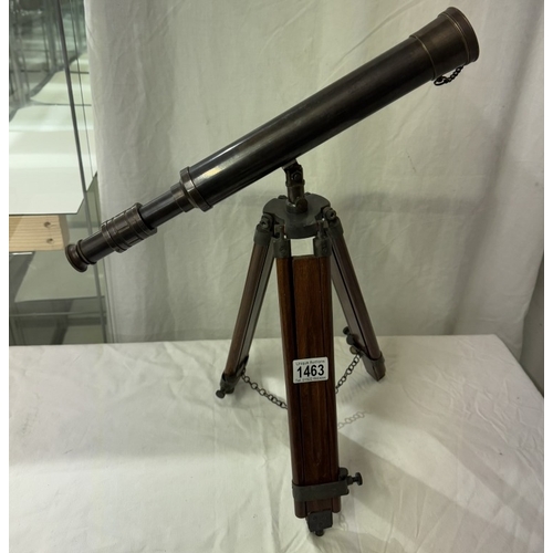 1463 - A patinated brass telescope on tripod base. Length 43cm