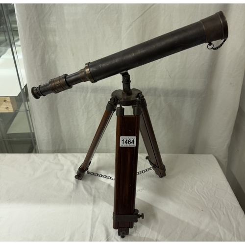 1464 - A patinated brass telescope on tripod base. Length 43cm