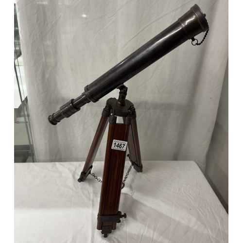 1467 - A patinated brass telescope on tripod base. Length 43cm