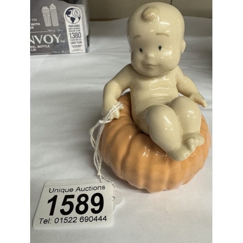 1589 - A NAO figure of a baby sat on a pumpkin.