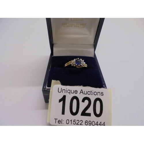 1020 - An un-marked yellow metal ring set central sapphire and diamonds, size K, 2.31 grams.