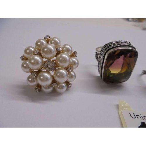 1043 - A silver ring set amber, two other silver rings and a yellow metal and pearl ring.