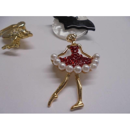 1050 - Four assorted brooches including pelican, bat, ballerina and a pair of clip on earrings.