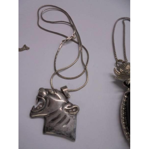 1057 - A silver tiger head pendant, a silver pendant set large stone and a silver locket.