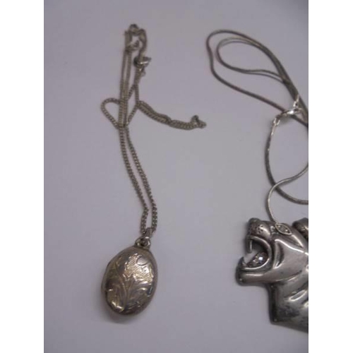 1057 - A silver tiger head pendant, a silver pendant set large stone and a silver locket.