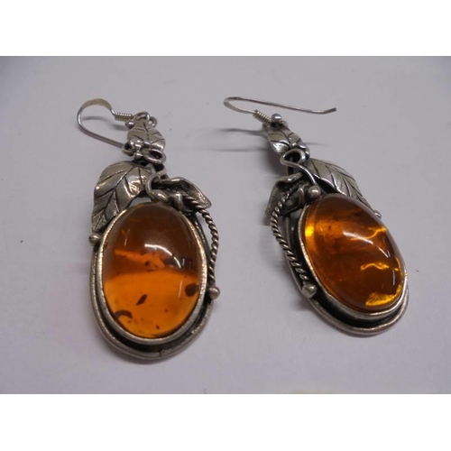 1064 - A pair of silver and amber pendant earrings.