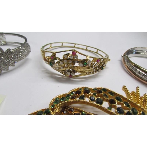 1071 - Three fashion bangles and a green stone set brooch.