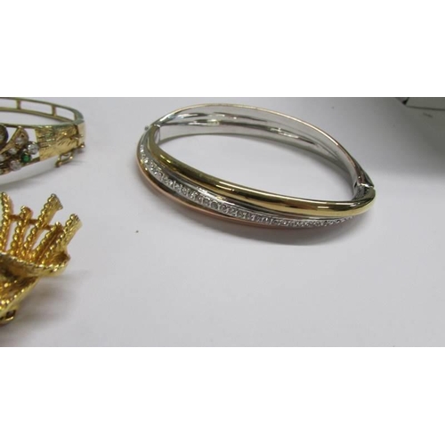 1071 - Three fashion bangles and a green stone set brooch.