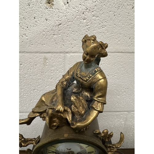 1740F - A 19th century gilt mantel clock surmounted figure with painted porcelain panels.