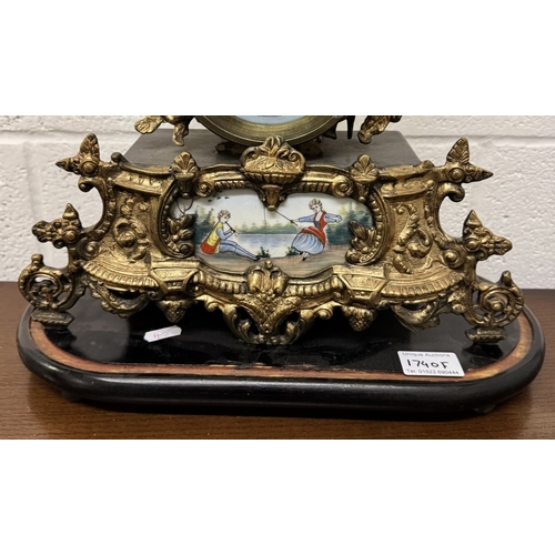 1740F - A 19th century gilt mantel clock surmounted figure with painted porcelain panels.