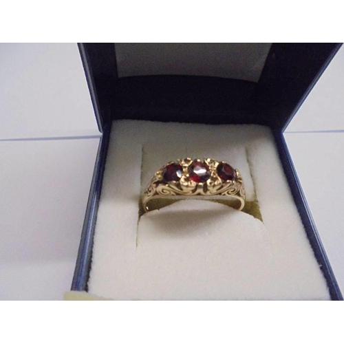 1128 - A vintage garnet set ring with 3 garnets in textured gold, Birmingham hall mark, size Q, 2.3 grams.