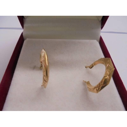 1140 - A pair of 9ct gold engraved ear hoops. 0.58 grams.