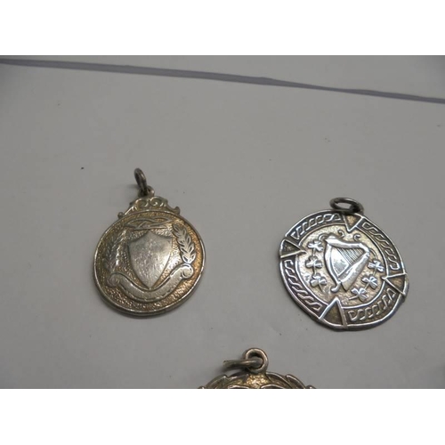 1147 - Four unmarked white metal watch fobs and a pendant.