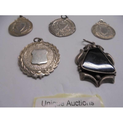 1147 - Four unmarked white metal watch fobs and a pendant.